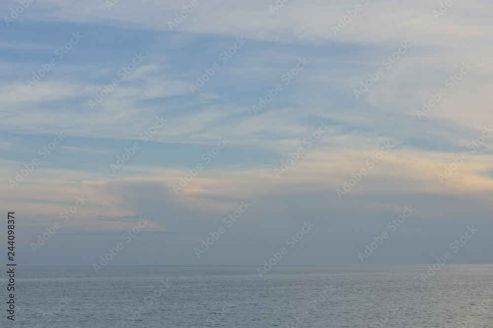 Natural background of cloudy sky above sea in sunset glare.