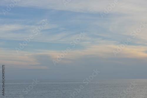 Natural background of cloudy sky above sea in sunset glare.