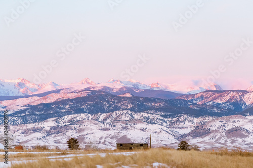 beautiful colorado sunrise with snow capped mountains and blue skies at the foothills of the rocky mountains