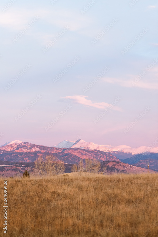 beautiful colorado sunrise with snow capped mountains and blue skies at the foothills of the rocky mountains