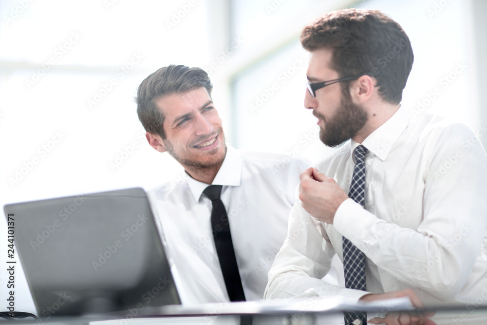 two business colleagues are discussing something sitting at the Desk two business colleagues are discussing something sitting at the Desk