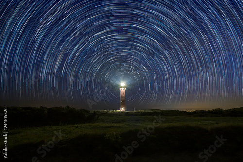 Lighthouse at night with star trails at the center