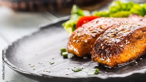 Delicious grilled roasted salmon fillets or steaks with sesame tomatoes and lettuce salad.