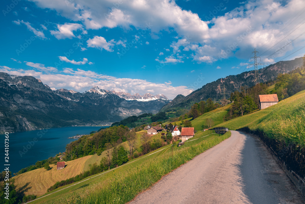 Road to Swiss village near a lake and the Alps