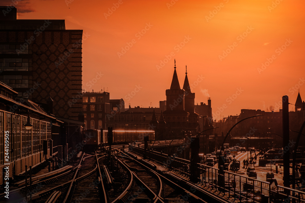 Berlin City skyline with sunset sky and train over Oberbaum Bridge  