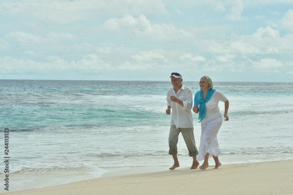 Portrait of happy elderly couple running on tropical beach