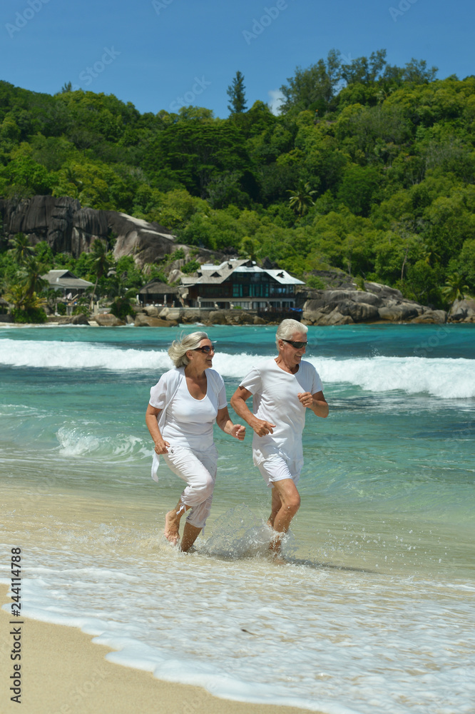 Portrait of happy elderly couple running on tropical beach Portrait of happy elderly couple running on tropical beach