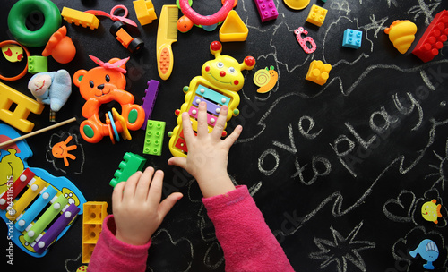 child is playing with bright toys on a black background