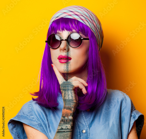 Young girl with purple hair and sunglasses on yellow background