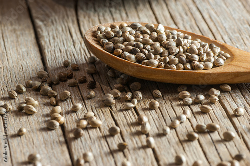 Heap of dried organic hemp seeds or cannabis plant seeds in spoon on wooden backdrop. cannabis herb concept. hemp seed used birdseed photo