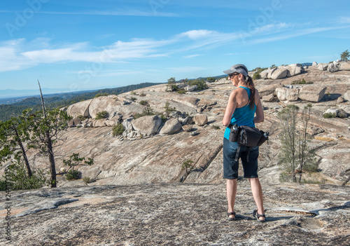 Older, woman hiker with waist pack enjoys rocky landscape view