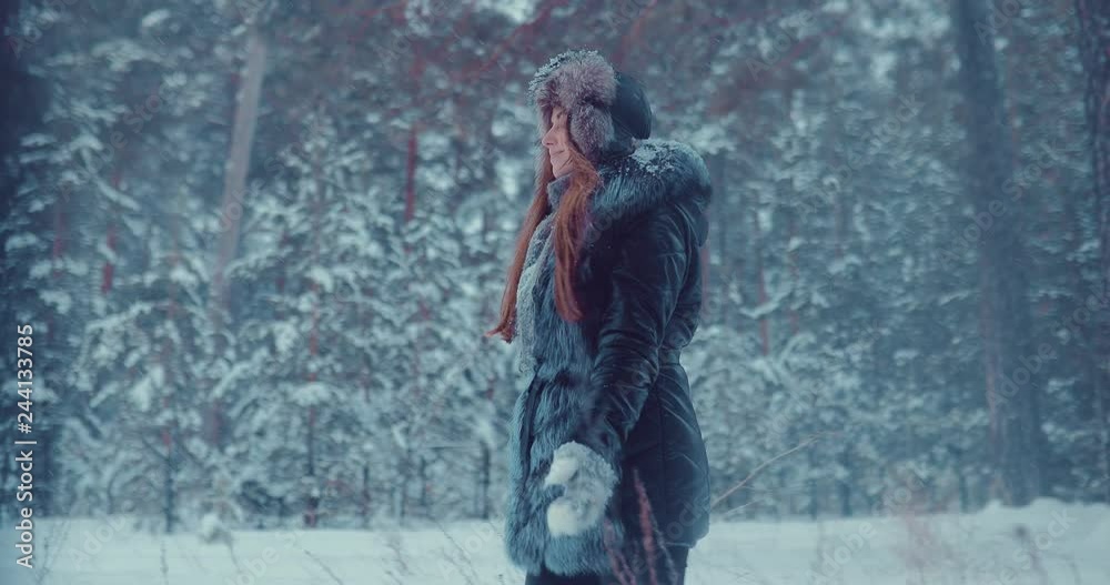 Pretty girl walks through the winter forest. Trees are covered with snow. Side view. Pretty girl walks through the winter forest. Trees are covered with snow. Side view.