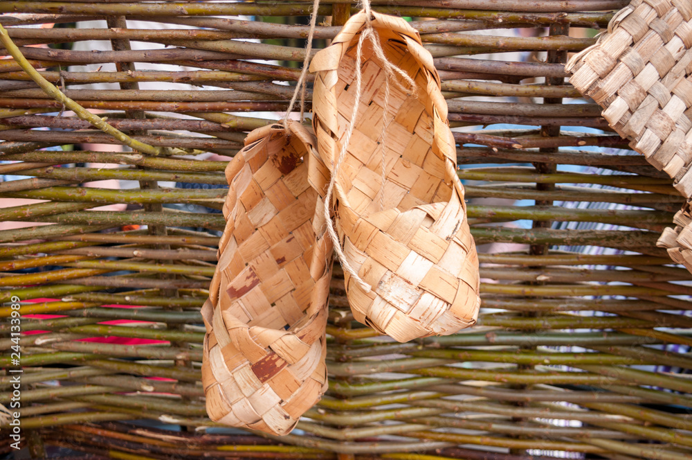 Obraz premium Russia, Khabarovsk, August 18, 2018: Folk handicrafts, bast shoes on a wicker fence at a harvest festival