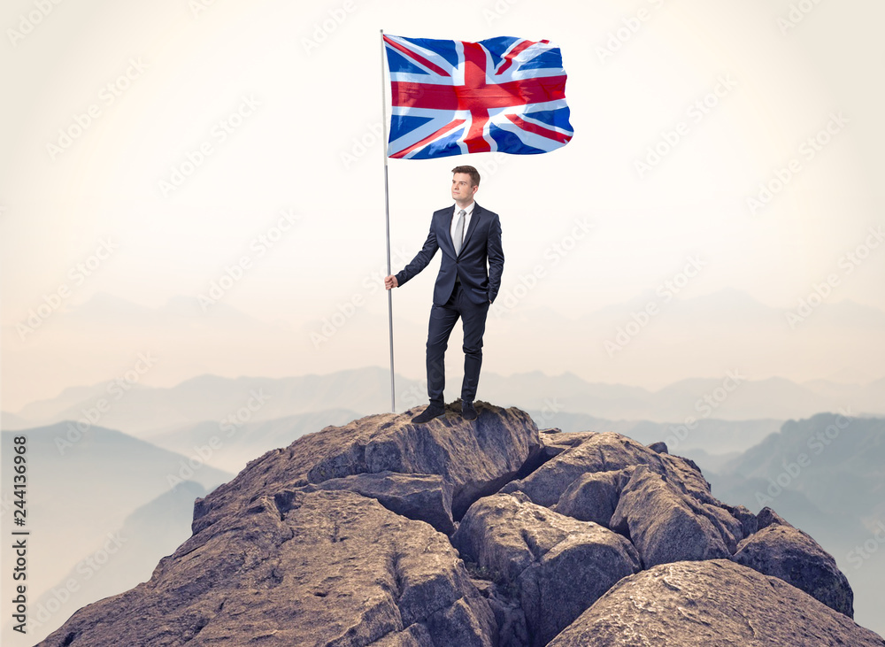 Obraz premium Successful businessman on the top of a mountain holding victory flag 