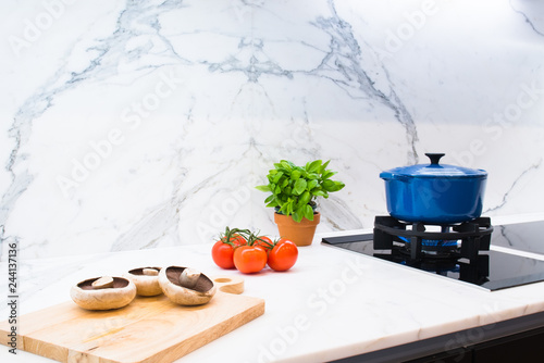 Quadro su tela Blue enamel pot cooking shown with ingredients of mushrooms, tomatoes and basil