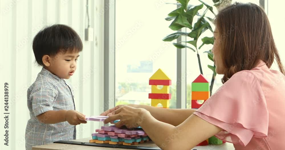 Asian toddler and his mother playing foam puzzle together, spending their free time, concept for mother and son. Asian toddler and his mother playing foam puzzle together, spending their free time, concept for mother and son.