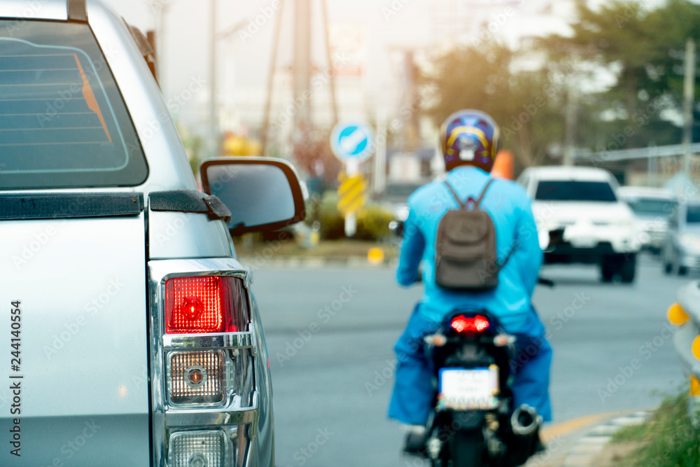 Silver pick up car open light break and motorcycle drivers with working uniform on the road stop by traffic junction on rush hour in the city. There is a car running from the opposite side, blurred. Silver pick up car open light break and motorcycle drivers with working uniform on the road stop by traffic junction on rush hour in the city. There is a car running from the opposite side, blurred.