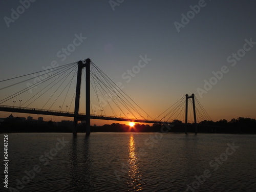 Suspension bridge over the river, illuminated by the setting sun in Krasnoyarsk city