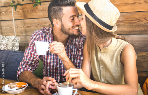 Young fashion lovers couple at beginning of love story - Handsome man kissing beautiful woman at coffee shop bar - Relationship concept with happy boyfriend and girlfriend together - Warm retro filter