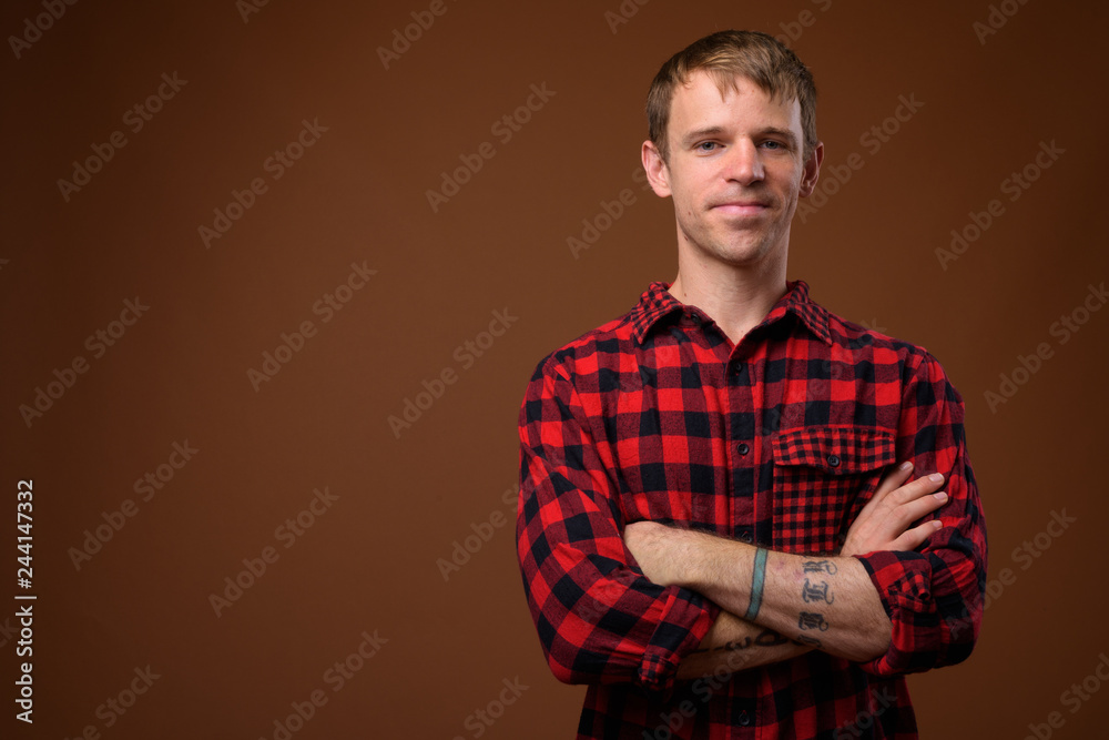 Man wearing red checkered shirt against brown background