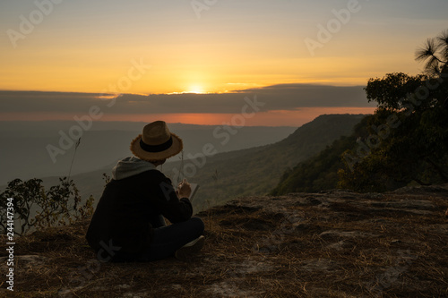 Woman sitting reading and writing looking out at beautiful natural view