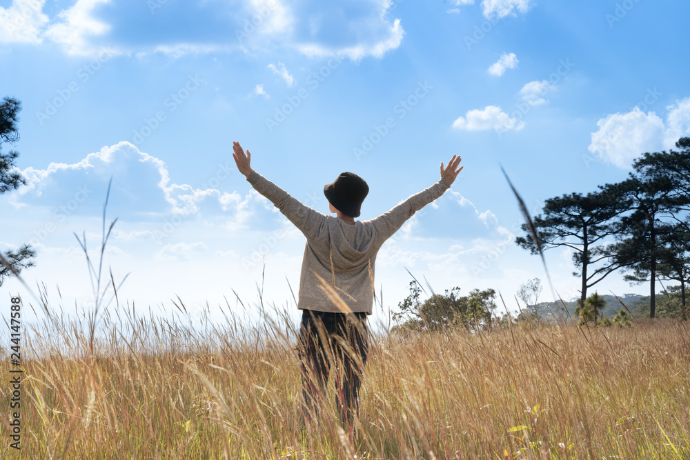 A person standing in large field enjoying the nature under beautiful blue sky A person standing in large field enjoying the nature under beautiful blue sky