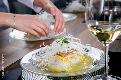 Chef decorates the halibut with mango sauce and rice noodles. Master class in the kitchen. The process of cooking. Step by step. Tutorial. Close-up