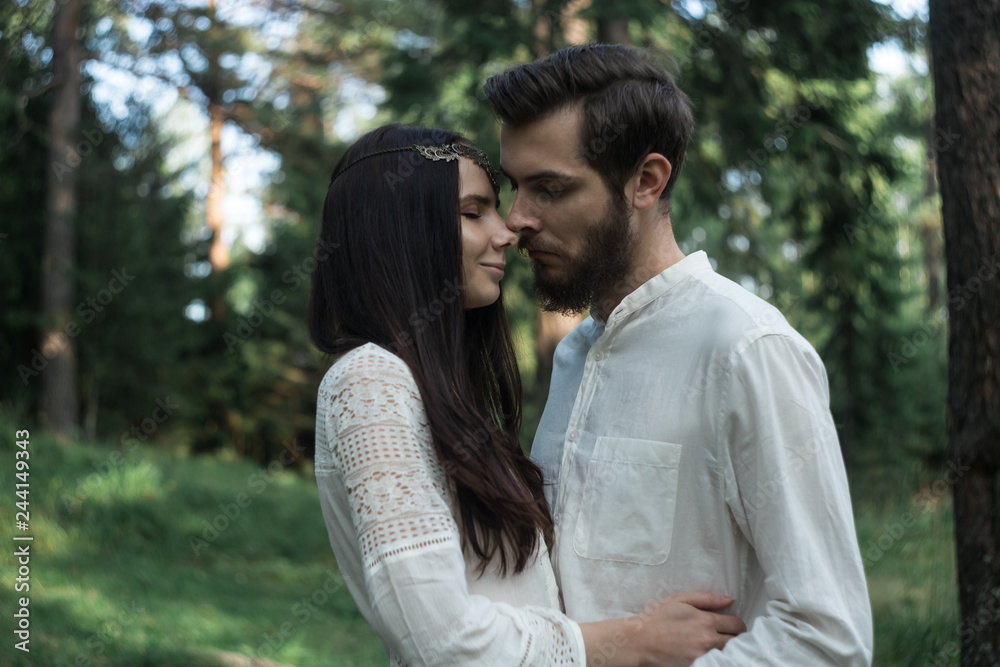 Young beautiful Slavic couple in love walks through the woods, sweet girl in a simple boho-style wedding dress. They are happy and calm. Golden hour, summer day, warm. They kiss, hug and hold hands. Young beautiful Slavic couple in love walks through the woods, sweet girl in a simple boho-style wedding dress. They are happy and calm. Golden hour, summer day, warm. They kiss, hug and hold hands.