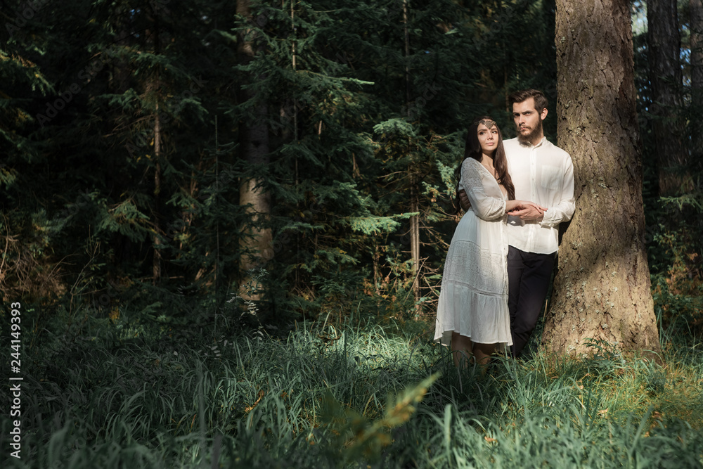 Young beautiful Slavic couple in love walks through the woods, sweet girl in a simple boho-style wedding dress. They are happy and calm. Golden hour, summer day, warm. They kiss, hug and hold hands. Young beautiful Slavic couple in love walks through the woods, sweet girl in a simple boho-style wedding dress. They are happy and calm. Golden hour, summer day, warm. They kiss, hug and hold hands.
