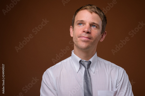 Businessman wearing white shirt against brown background