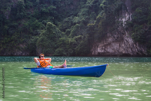 Happy man sitting in a kayak boat on a lake relaxing