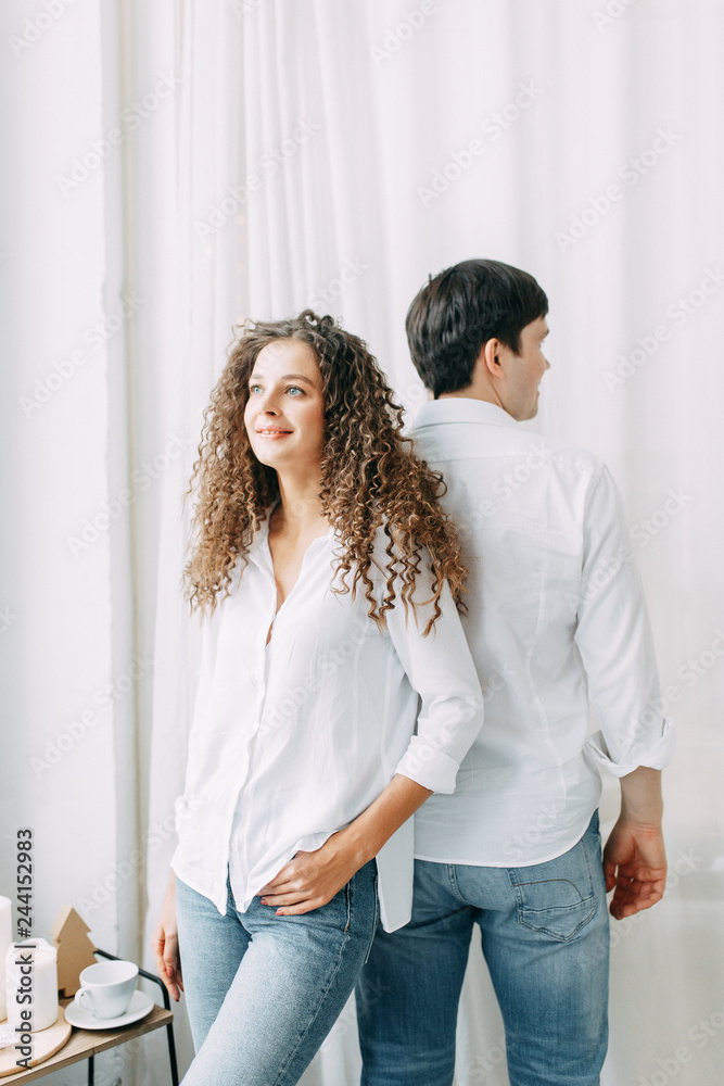 Young couple hugging and fighting not the bed. Photo shoot in bright interior Studio in European style. Young couple hugging and fighting not the bed. Photo shoot in bright interior Studio in European style.