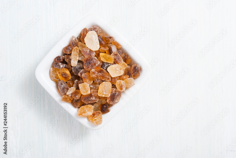 rock sugar in square dish, on white  wooden surface