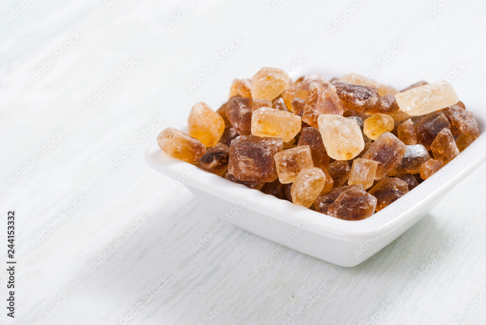 rock sugar in square dish, on white wooden surface rock sugar in square dish, on white wooden surface