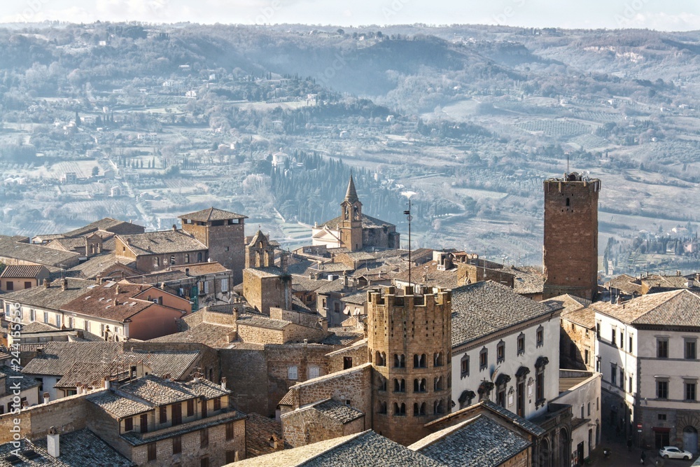 Obraz premium An Italian hilltop town sits high above the countryside in the distance.