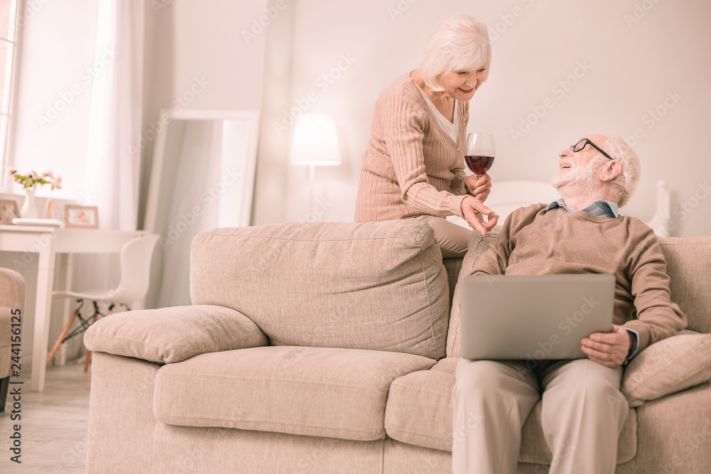 Pleased retired woman pointing at screen of laptop