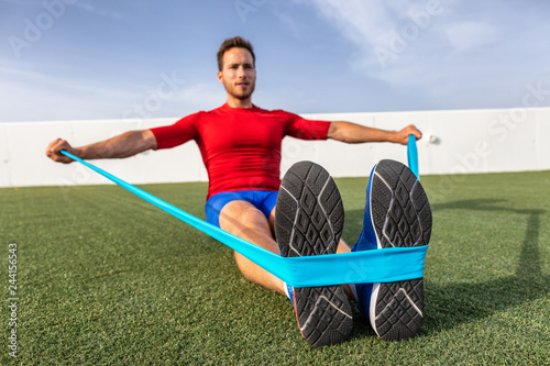 Fitness man training arms with resistance bands at outdoor gym or home garden. Body workout with equipment outside. Elastic rubber band accessory.