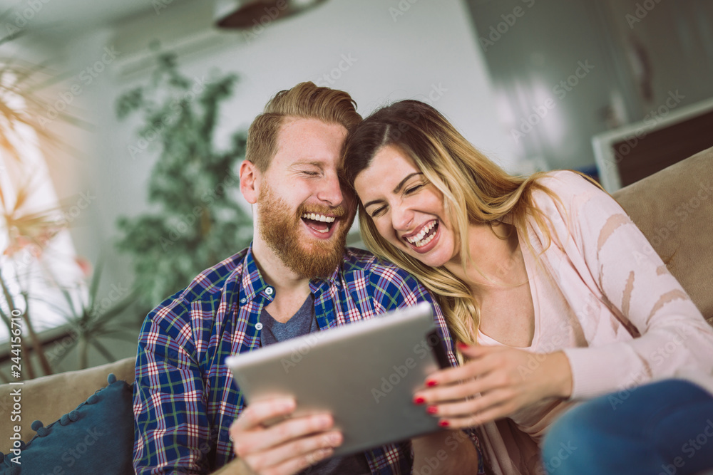 Couple in love sitting on the sofa and using tablet, having fun. Couple in love sitting on the sofa and using tablet, having fun.