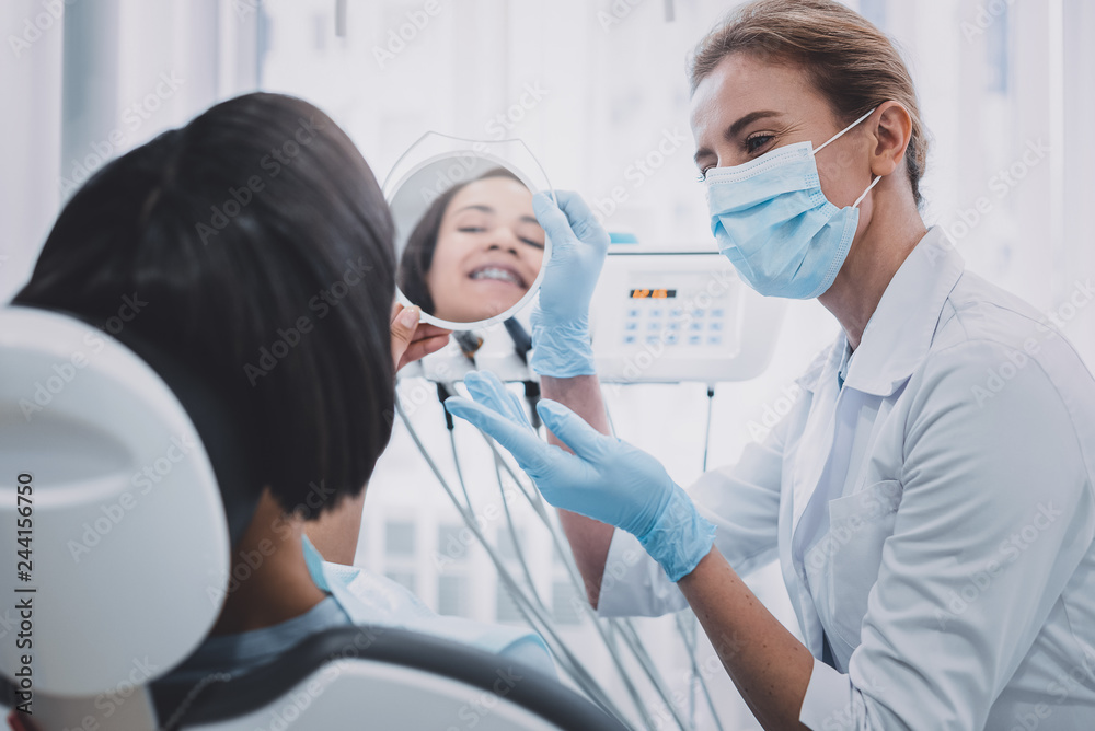Kind dentist demonstrating result of her job Kind dentist demonstrating result of her job