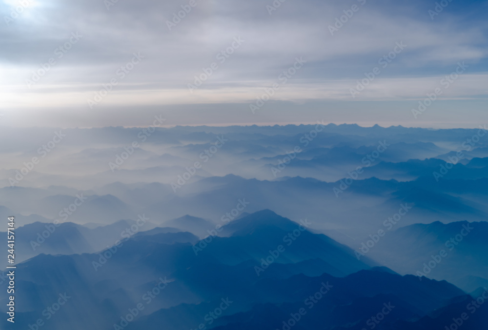 The tops of a mountains is being covered by beautiful sunlight. View from a plane