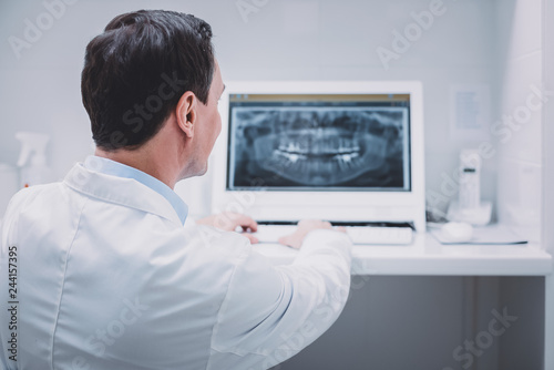 Pleased young stomatologist checking teeth of his patient