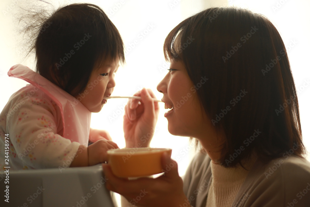 赤ちゃんに離乳食を与える母親 赤ちゃんに離乳食を与える母親
