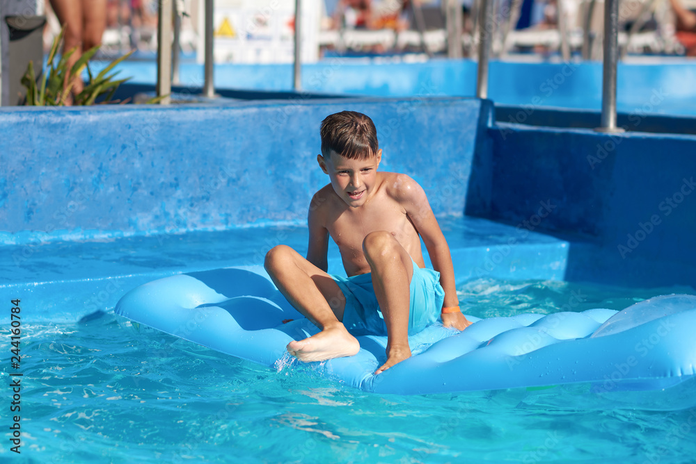 Caucasian boy sitting on inflatable mattress in swimming pool at resort.