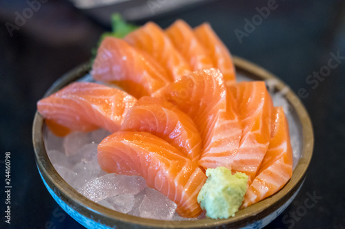 Salmon sashimi with vegetable and ice in a bowl, served in a restaurant