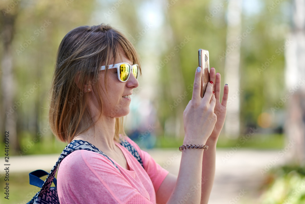 European woman is travelling along the beautiful and picturesque park and taking selfie.