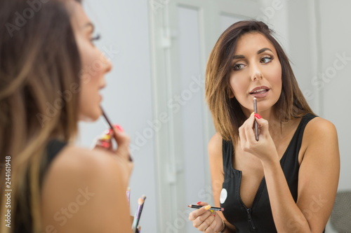 Foto Beautiful young woman applying lip-liner pencil.