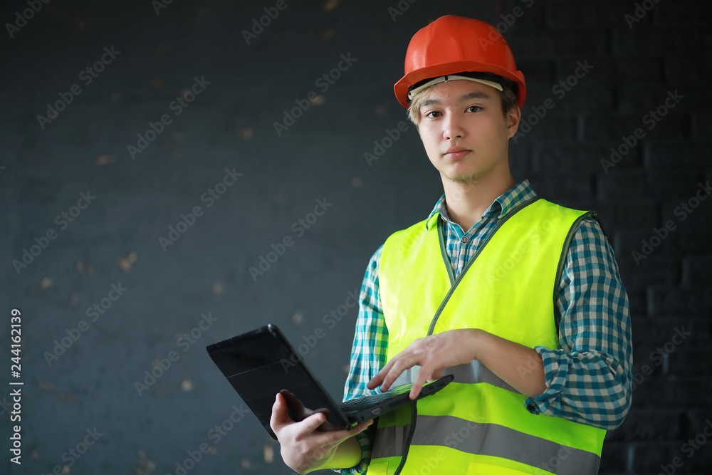 Asian man in protective helmet and construction waistcoat
