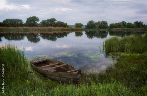 Spring morning on the river Southern Bug. At the coast in the reeds is a wooden boat.