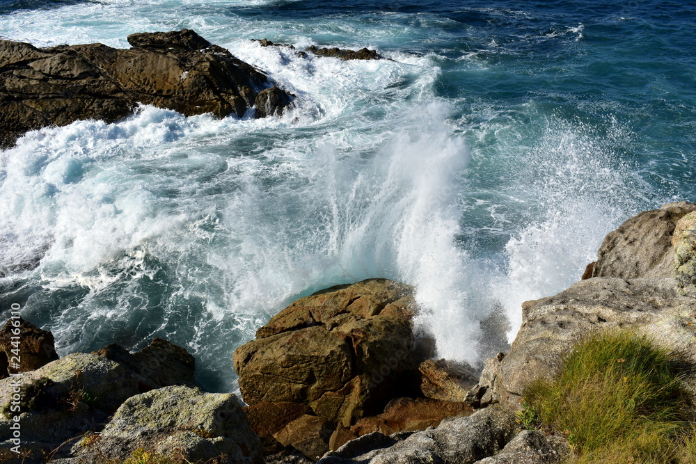 Wild waves splashing against the rocks. Blue sea with white foam, Galicia, Spain.