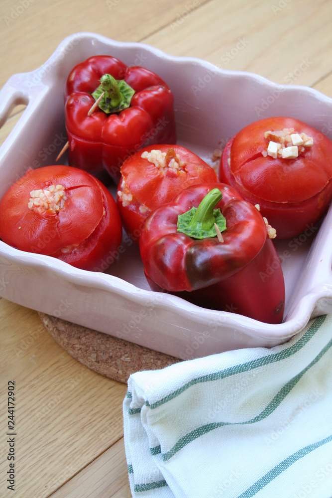 Baked red peppers and tomatoes stuffed with rice on wooden table Baked red peppers and tomatoes stuffed with rice on wooden table
